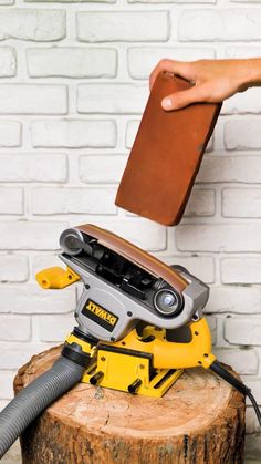 a person holding a book over a stump with a power tool on top of it