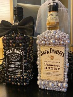 two bottles of jack daniels whiskey on a table next to a bag with pearls and a bow