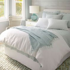 a bed with white and blue sheets in a bedroom