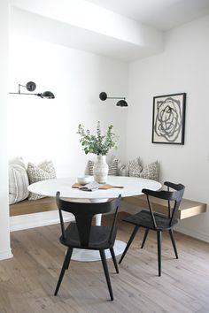 a dining room table with two chairs and a bench in the corner next to it