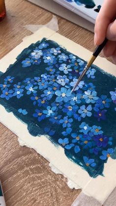 someone is painting flowers on a piece of paper