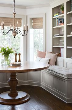 a dining room with a bench and table in it's centerpiece, along with built - in bookshelves