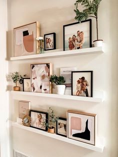 some white shelves with pictures and plants on them