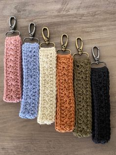 six crocheted key fobs are lined up on a table