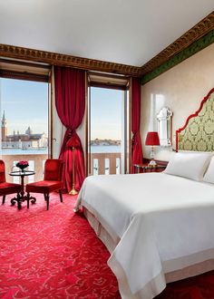 a hotel room with red carpeting and large windows overlooking the water in front of it