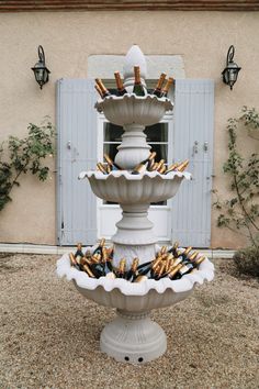 a fountain filled with lots of bottles and wine glasses on it's sides in front of a building