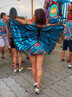 two women dressed in butterfly costumes walking down the street with their arms around each other