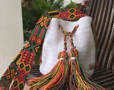 a white bag with multicolored tassels sitting on top of a wooden bench