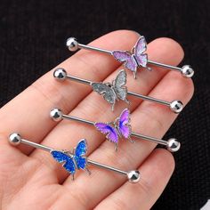 four different colored butterflies are attached to the back of a pair of surgical steel barbells