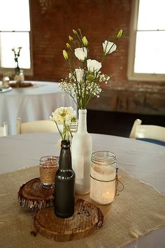 flowers in vases are sitting on a table with mason jars and candles around it