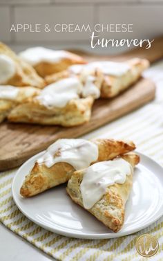 apple turnovers with icing on a plate next to an apple and cutting board