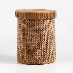 a woven basket with a wooden lid and white string tied around the top, sitting on a white surface