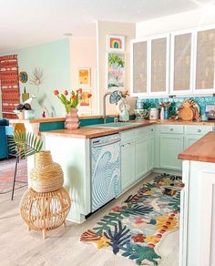 the kitchen is decorated in pastel colors and has an area rug on the floor