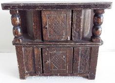 an old wooden cabinet with carvings on the front and sides, sitting against a white wall
