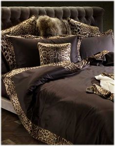 a leopard print comforter and pillows on a bed with a black velvet headboard