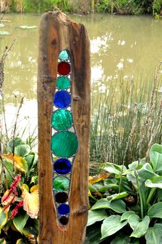a garden sculpture made out of recycled glass bottles and wood sticks with flowers in the background