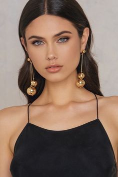 a woman wearing gold earrings and a black top