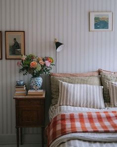 there is a bed with plaid sheets and pillows on the headboard in this bedroom