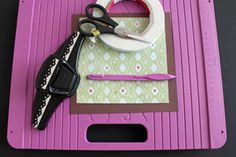 a pair of scissors sitting on top of a pink cutting board