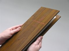 a person holding an open wooden book in their hand