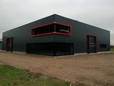 an industrial building with red trim on the front and side windows is shown in this photo