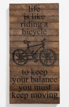 a wooden sign that says life is like riding a bicycle to keep your balance you must keep moving