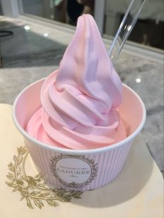 a pink ice cream in a cup with a spoon