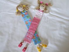 two stuffed dolls are laying on a white sheet with one holding the other's arm