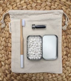 the contents of a travel kit are laid out on a woven mat, including toothbrushes and other items