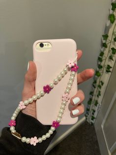a woman is holding up her phone case with pearls and flowers on the back,