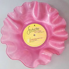 a pink plastic flower shaped object with a yellow label on the center and bottom part