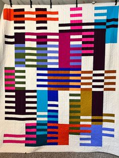a multicolored quilt hanging on a wall