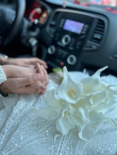 a white flower sitting on top of a car floor next to a person's hand