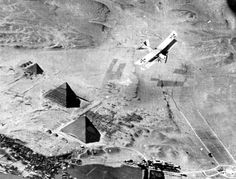 an airplane flying over some pyramids in the middle of the desert with other structures around it