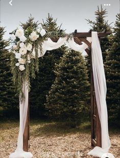 a wedding arch decorated with white flowers and greenery