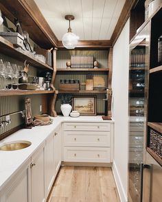 a kitchen filled with lots of wooden shelves and white counter top next to a sink