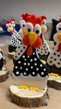 there are some chicken figurines sitting on the tree stumps that have been decorated with polka dots
