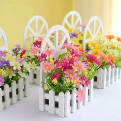 colorful flowers are placed in small white planters