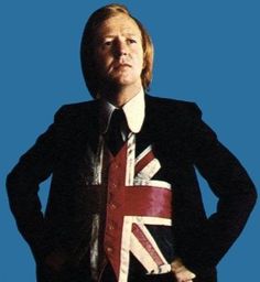 a man in a suit and tie with the british flag on his shirt over his shoulders