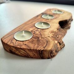 three tealight candles are placed on a piece of wood