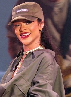 a woman wearing a hat and smiling while standing in front of a stage with other people