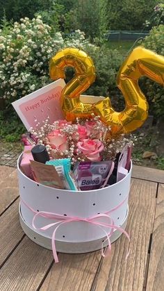 a birthday gift in a bucket with the number twenty on it's side and balloons
