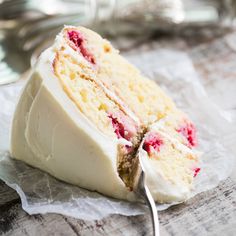 a piece of cake with white frosting and raspberries