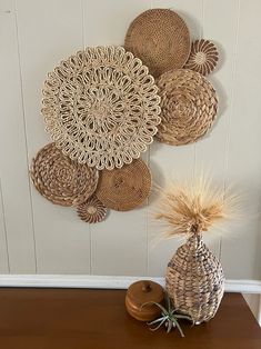 some baskets are hanging on the wall near a vase with grass in it and a potted plant