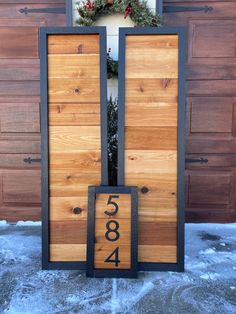 a wooden door with numbers on it in front of a house that is decorated for christmas