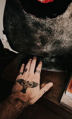 a person's hand on top of a table next to a book