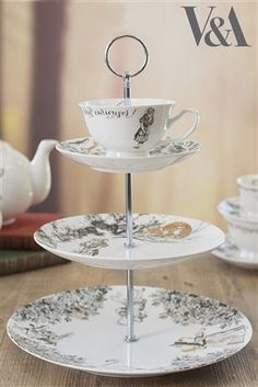 three tiered plates with tea cups and saucers on them, sitting on a table