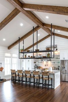 an open kitchen with wooden floors and white walls, along with exposed beams on the ceiling
