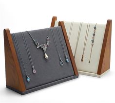 three necklaces are on display in wooden cases