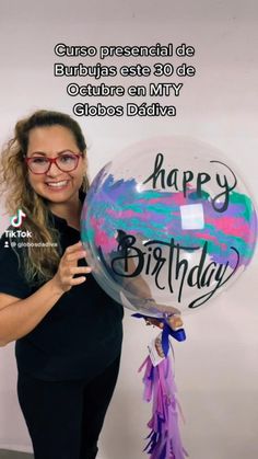 a woman holding a birthday balloon with the words happy birthday written on it in spanish